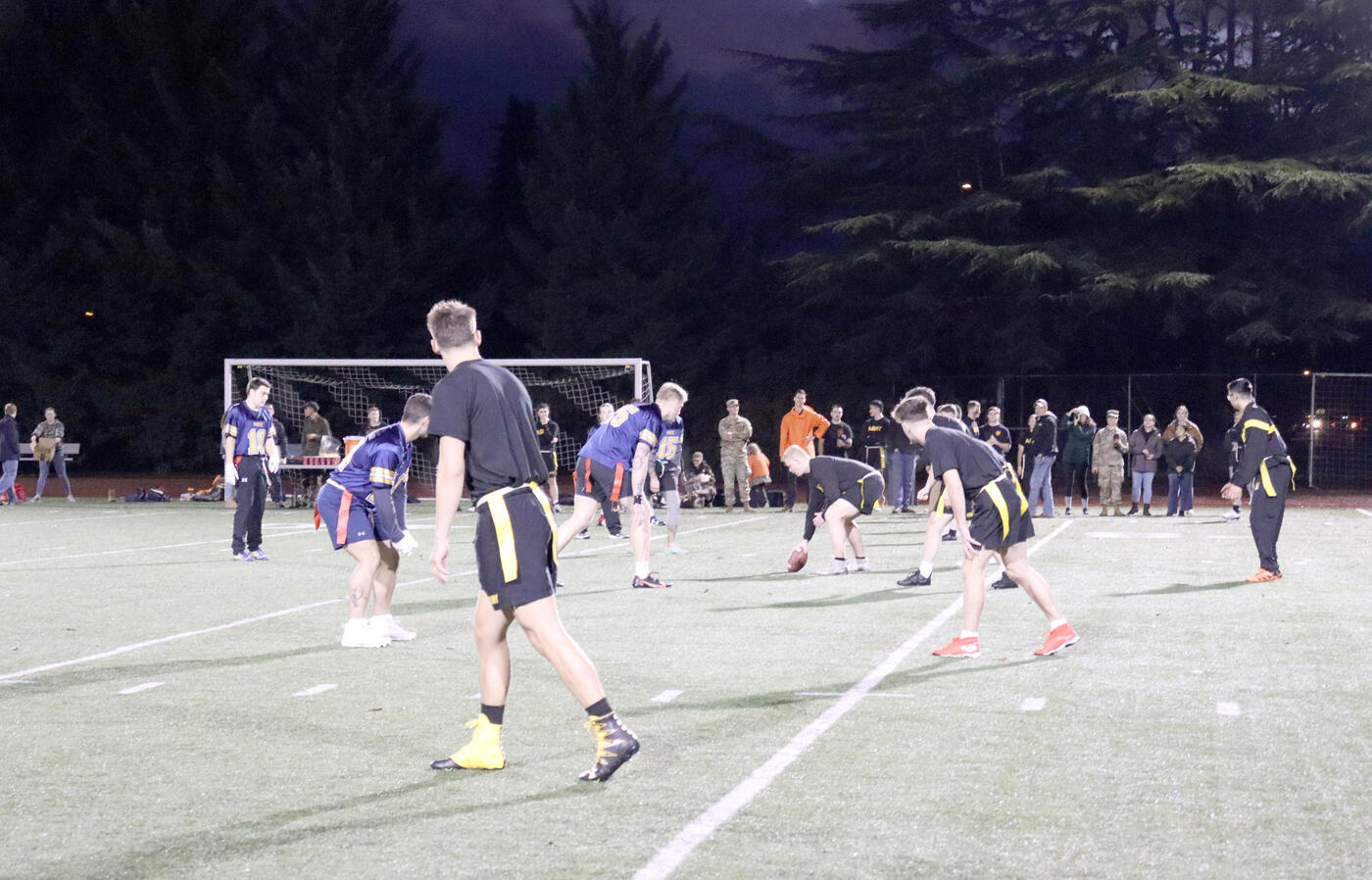 Students on a Football field ready to snap the ball. 