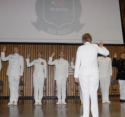 Military students standing in line, raising their hand to take their oath.