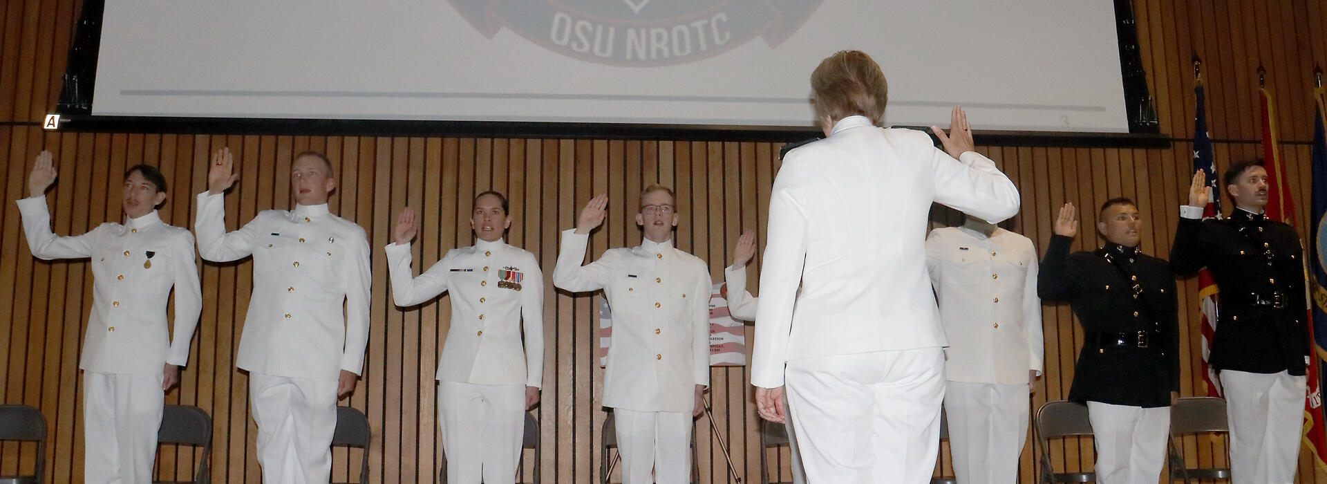Military students standing in line, raising their hand to take their oath.