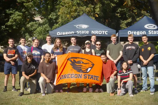 Students posed around an orange Oregon State Beavers flag. 