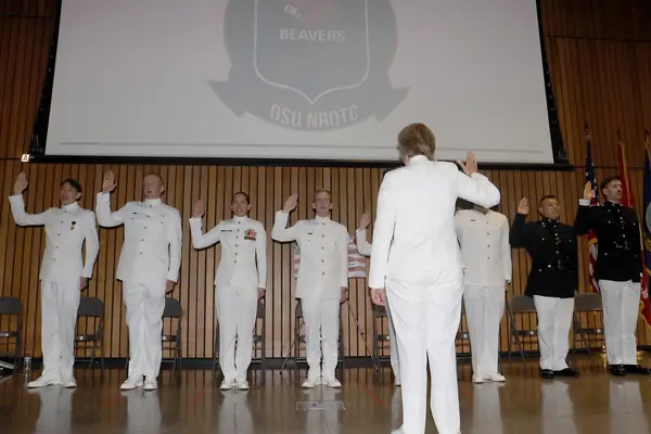 Military students standing in line, raising their hand to take their oath.